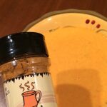 Spice jar beside bowl of creamy orange soup